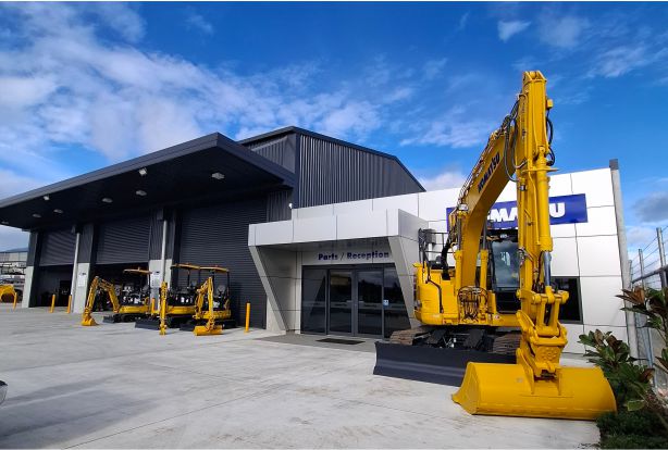 Yellow digger outside Komatsu workshop with blue sky background
