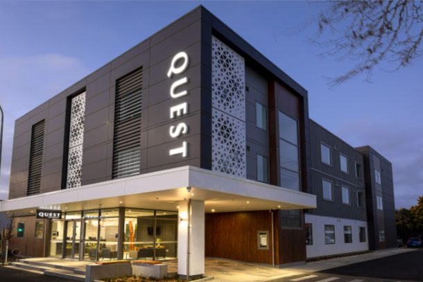 Architect rendering of a Quest hotel at dusk with lobby lights on