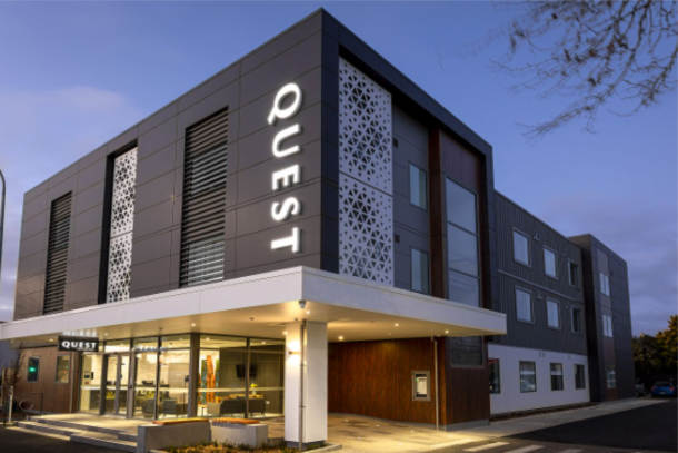 Architect rendering of a Quest hotel at dusk with lobby lights on
