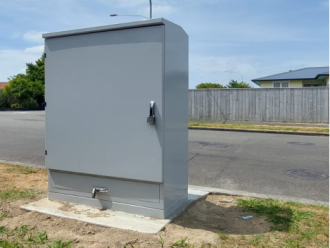 grey kiosk for a wastewater pump on the side of the road